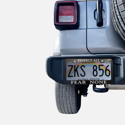 GoPlates custom black anodized aluminum license plate frame with laser engraved text mounted on a silver SUV bumper.
